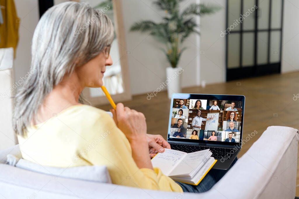 Side view a middle aged female entrepreneur using laptop for video call