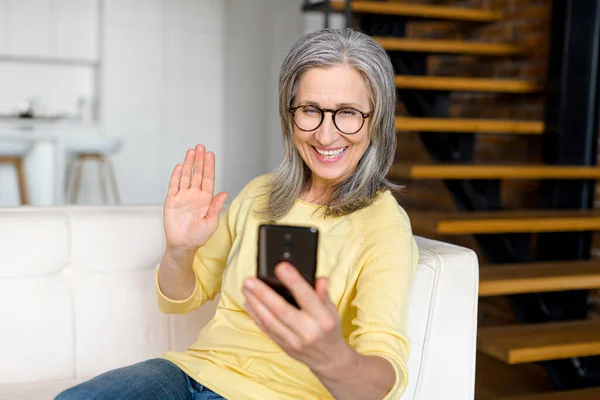Позитивна старша зріла дама в жовтому джемпері розмовляє онлайн по телефону — стокове фото