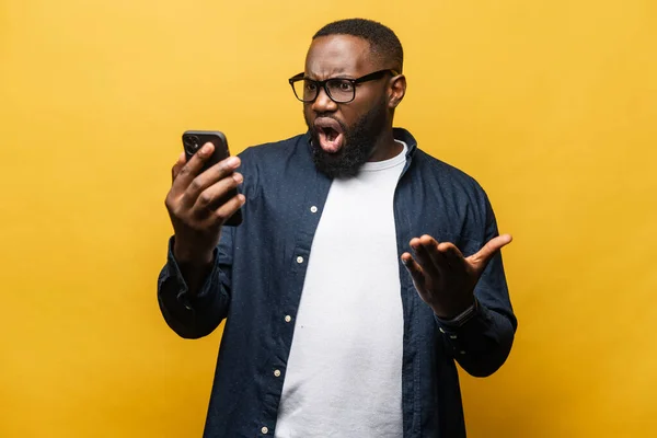 Chockad förvånad afroamerikansk man stirrar på smartphone — Stockfoto