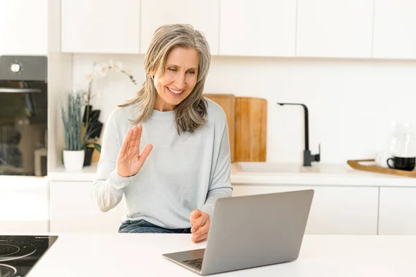Гарна старша зріла жінка використовує ноутбук для відеозв'язку — стокове фото
