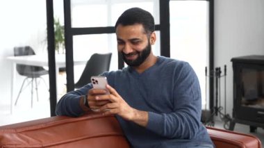 Neşeli Hintli adam günlük kıyafet giyip mesajlaşıyor, akıllı telefondan mesajlaşıyor.
