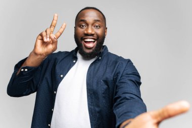 Gülümseyen ve kameraya bakan komik Afro-Amerikan genç adam.