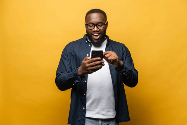 Porträtt av glad ung svart kille skicka meddelande på mobiltelefon — Stockfoto