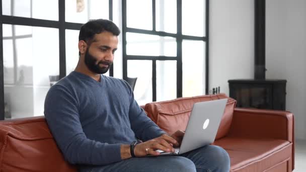 Умный индийский фрилансер, использующий ноутбук для удаленной работы из дома — стоковое видео