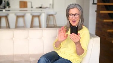 Olgun, gri saçlı bir kadının cep telefonuyla video bağlantısı ile konuşmasına sevindim.