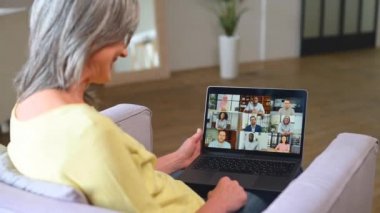 Gri saçlı yaşlı kadın iş arkadaşlarıyla online iletişim kurmak için online platformu kullanıyor