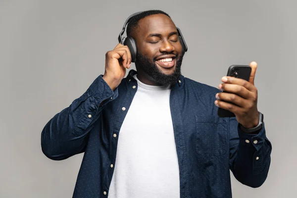 Roliga afroamerikanska mannen bär hörlurar med hjälp av en smartphone — Stockfoto