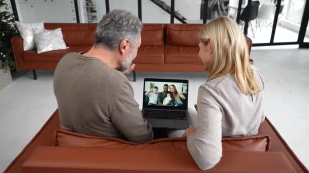 Весела пара середнього віку використовує ноутбук для відеозв'язку. Вид ззаду — стокове відео