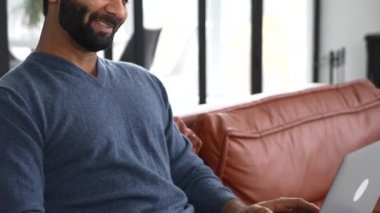 Video bağlantısı için laptop kullanan yakışıklı, sakallı Hintli adam.