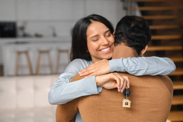 젊은 아내의 손에 들고 있는 열쇠에 초점을 맞추고, 남편은 아내를 껴안고 있다 — 스톡 사진