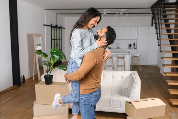 Vrolijke Indiase man houdt gelukkige vrouw in de armen staande in appartement — Stockfoto