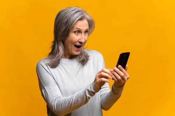 Ohromený senior žena držení a používání smartphone — Stock fotografie