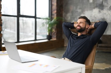 Genç bir erkek ofis çalışanı sandalyeye yaslandı ve rahatladı.