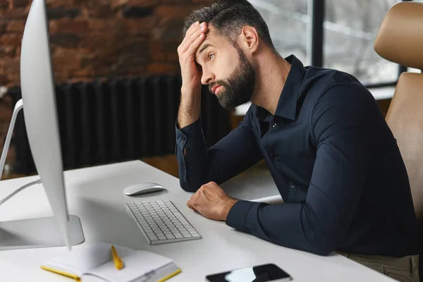 Deprimido jovem funcionário do escritório masculino está olhando para monitor de computador — Fotografia de Stock