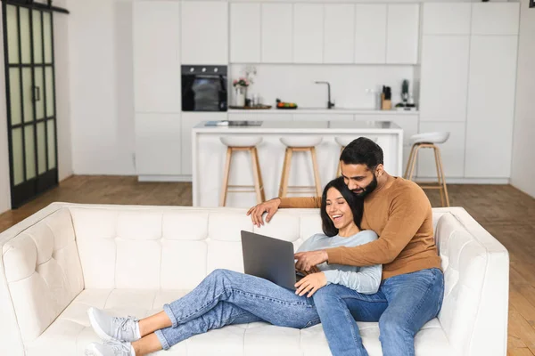 Coppia allegra innamorata di trascorrere il tempo libero online con un computer portatile a casa. Giovane donna e uomo guardando lo schermo del computer portatile mentre si siede sul divano, guardando film comici — Foto Stock