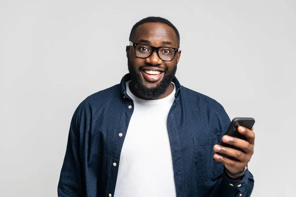 Iloinen Afrikkalainen Amerikan nuori mies tilalla älypuhelin — kuvapankkivalokuva