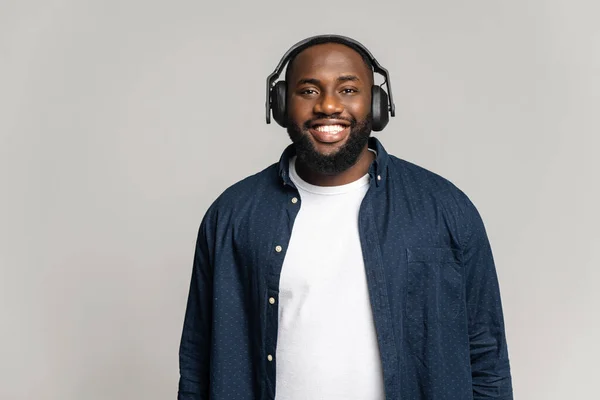 Lächelnder Afroamerikaner mit drahtlosen Kopfhörern, der in die Kamera schaut — Stockfoto