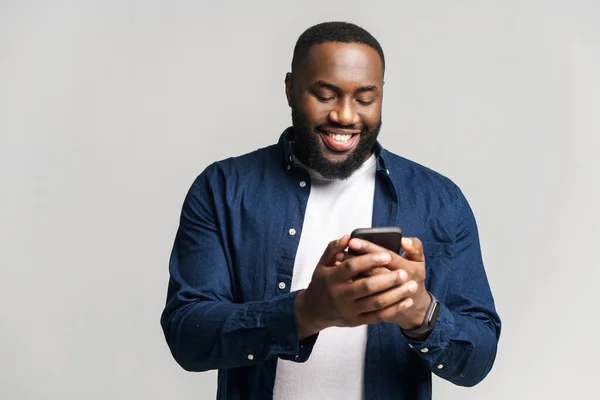 Optimistisk afro-amerikansk man bär casual skjorta sms på smartphone — Stockfoto