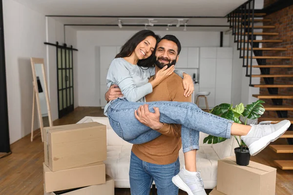 Pakistaanse man tilt en omarmt zijn vrouw terwijl hij viert dat hij naar een nieuw appartement verhuist. Huis van onze eigen, blij om te verhuizen naar een nieuw huis — Stockfoto