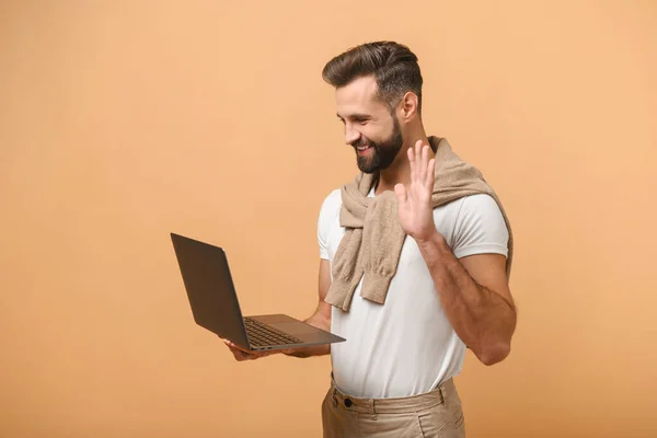 ウエストアップビューの若い男の白いtシャツ手で手を振ってこんにちはながら、オレンジに隔離された誰かとノートパソコンを介してチャット — ストック写真
