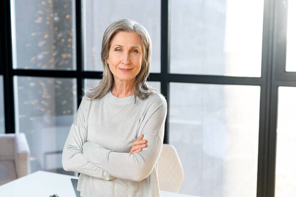 Портрет элегантной зрелой бизнесвумен средних лет со сложенными руками