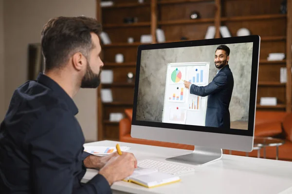 Conferenza virtuale. Giovane uomo che indossa auricolare utilizzando il pc per videochiamata, avendo video incontro con diverse persone insieme. Lavoro a distanza — Foto Stock