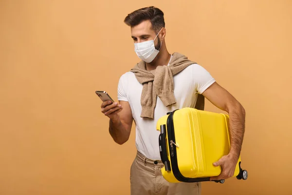 Δείτε το πορτραίτο του άνδρα με την προστατευτική μάσκα και κοιτώντας το smartphone του ενώ τσεκάρει τα εισιτήριά του στο πορτοκαλί. — Φωτογραφία Αρχείου