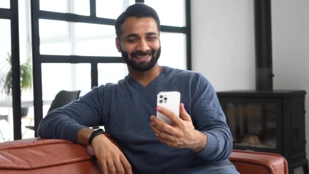 Счастливый молодой бородатый индеец с востока держит телефон и машет привет — стоковое видео