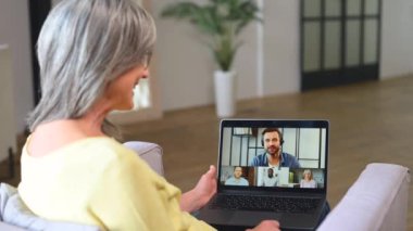 Koltuğunda oturan ve video bağlantısı için laptop kullanan çağdaş son sınıf öğrencisi kadın.