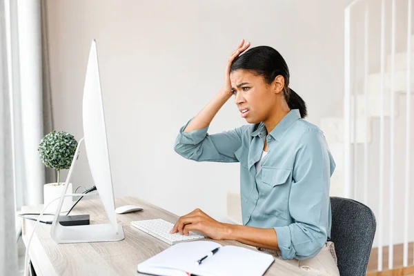 Tired business woman sitting with computer at home and has a problem with remote work. Frustrated woman touching with hand to her head — Fotografia de Stock