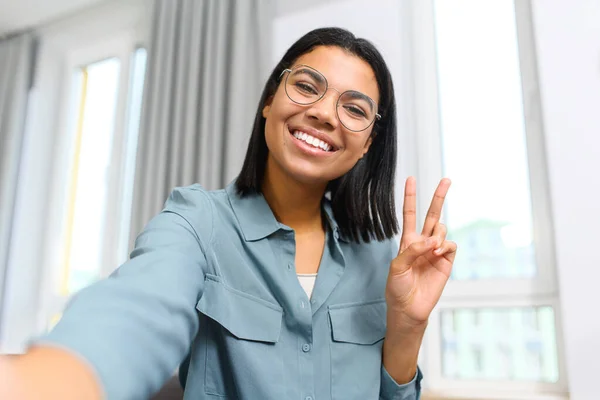 Young and energetic multiracial female making selfie or having video call, while spending time at home and waving at the camera, saying hello. Job hunting — 스톡 사진