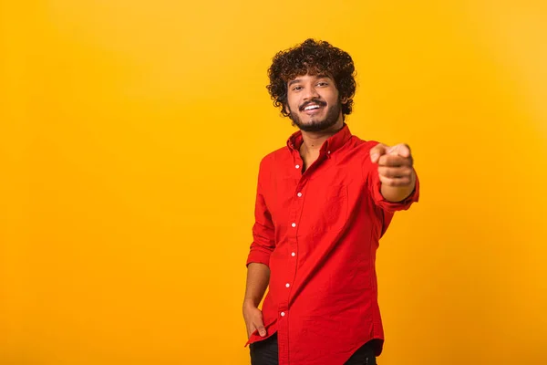 Portrait of man with curly hair wearing red casual style T-shirt, pointing finger pistols to camera playfully and flirting, choosing lucky winner. Indoor studio shot isolated on orange — 图库照片
