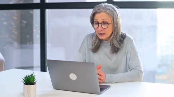 Mujer de negocios senior de pelo gris de confianza que utiliza el portátil para la comunicación virtual — Vídeos de Stock