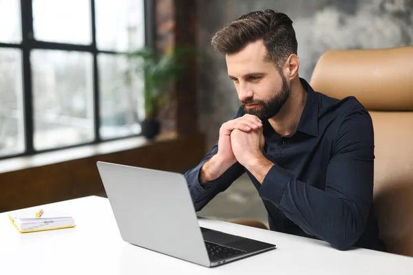 Yoğunlaşmış adamın ofisten bakarken laptopa ciddi bir ifadeyle baktığı yüksek açılı görüntü. İş yerindeki ciddi adam. — Stok fotoğraf