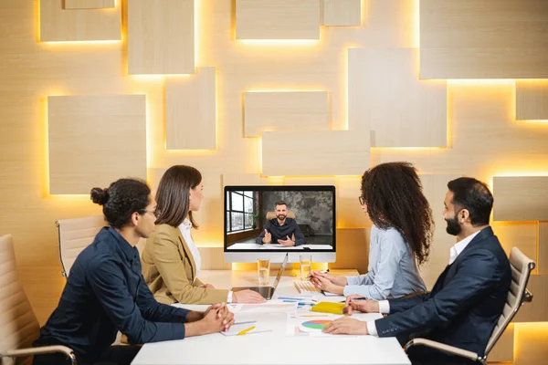 Óptima equipa. Grupo de pessoas ativas estão tendo brainstorming em um ambiente de escritório positivo com seu colega via videochamada — Fotografia de Stock
