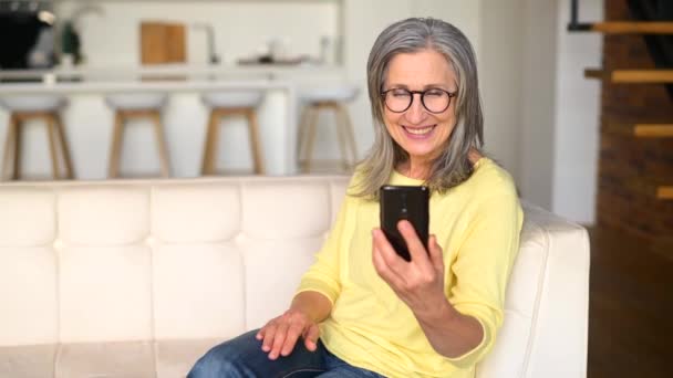 Θετική ώριμη ηλικιωμένη κυρία σε ένα κίτρινο άλτη μιλώντας στο τηλέφωνο — Αρχείο Βίντεο