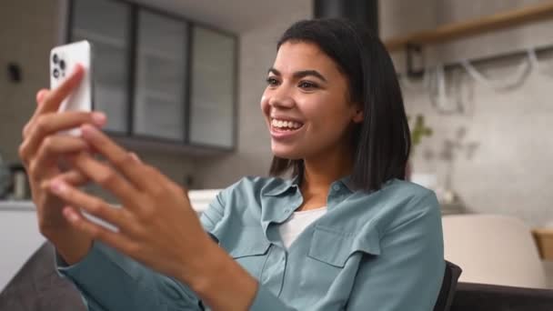 Video görüşmesi için cep telefonunu kullanan neşeli, çok ırklı genç bir kadın. — Stok video