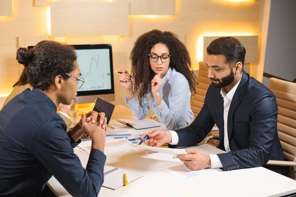 Piena concentrazione sul lavoro. Gruppo di giovani uomini d'affari che lavorano alla scrivania con i colleghi del grande ufficio spazioso — Foto Stock