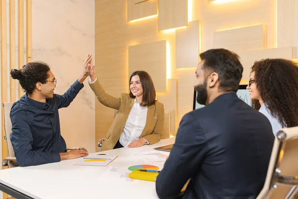 Uomini allegri che danno il cinque alla sua graziosa collega. Un altro membro del team li guarda e sorride — Foto Stock