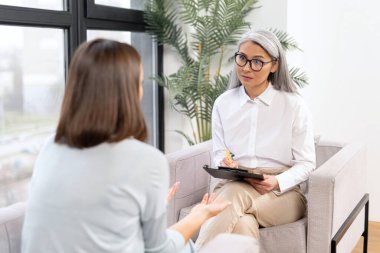 Mature senior therapist expresses support and empathy to a upset female patient during therapy session. Mental health