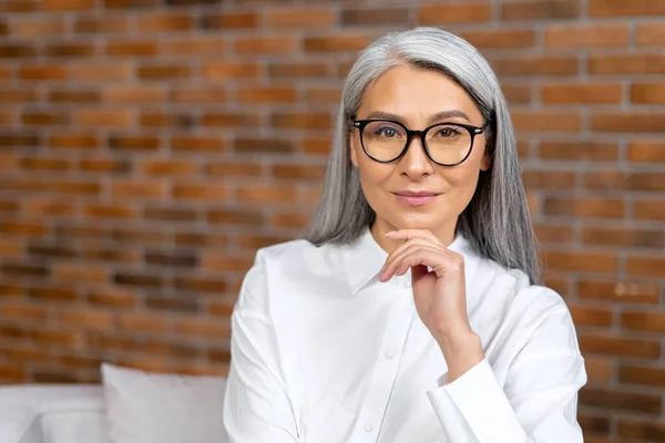 Retrato de cerca de una mujer mayor contemporánea que usa gafas elegantes mirando a la cámara y sonríe. Anciana descansando en la oficina, descansando — Foto de Stock