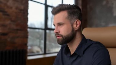 Excited caucasian man sitting at the table, looking at the computer screen and rejoicing