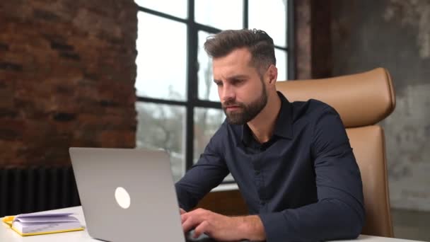 Doubtful caucasian guy sitting at the table at the office. Frustrated pensive man worried — Vídeo de Stock