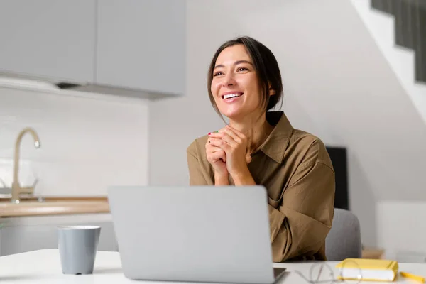 ノートパソコンで仕事をしながら朝のコーヒーを楽しむ若い陽気なアジアの女性を笑顔で、自宅のオフィスの机に座っています。幸せな実業家 — ストック写真