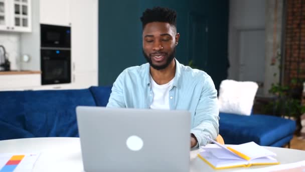 Videogesprek. Vrolijke aantrekkelijke multiraciale kerel is met behulp van laptop voor video communicatie — Stockvideo