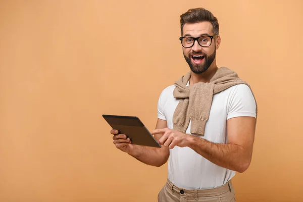 Portrait d'homme barbu ravi avec tablette se réjouissant de quelque chose tout en posant isolé sur orange — Photo