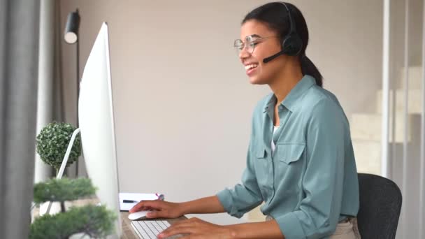 Fröhliche multiethnische junge Frau nutzt Computer für Fernarbeit im Home Office — Stockvideo