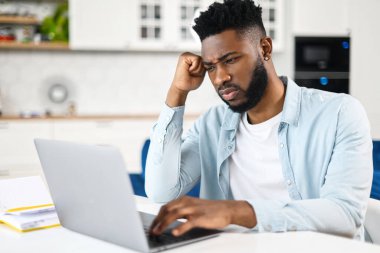 Kanepede oturan, bilgisayar başında sürekli çalışmaktan yorgun hisseden, şakağına dokunan, baş ağrısı çeken çok ırklı erkek ya da öğrenci.