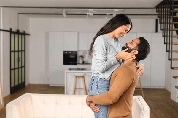 Веселий індіанець, який тримає щасливу жінку в руках, стоячи в квартирі. Етнічні латиноамериканці закохуються в переселення у власну квартиру. Перемістити в новий будинок. — стокове фото