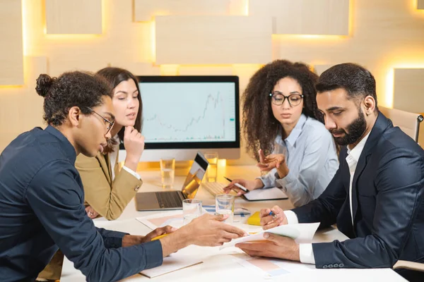 Making great decisions. Young beautiful woman sitting with her colleagues and discussing something with serious expression while her coworkers listening to her sitting at the office — Stock Photo, Image